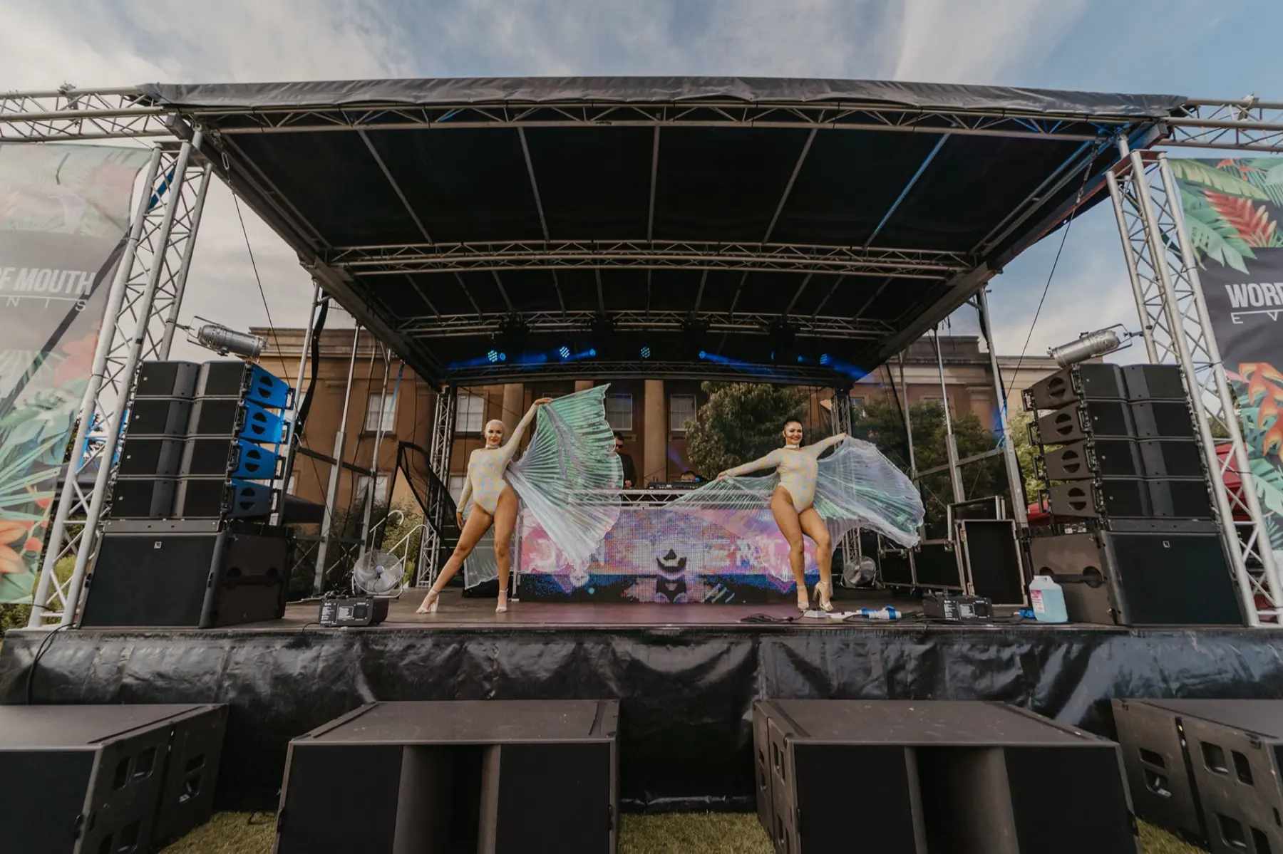 Outdoor festival stage production with dancers, lighting and line-array sound